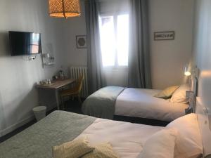 um quarto de hotel com duas camas e uma secretária e uma televisão em Hôtel L'Estran em Trouville-sur-Mer