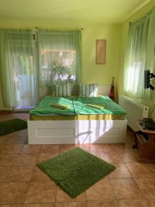 a bedroom with a bed with green sheets and windows at Panni Vendégház in Egerszalók