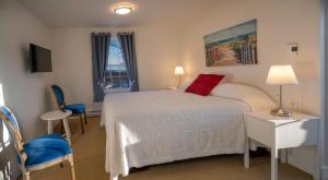 a bedroom with a white bed and a window at Telegraph House Motel in Baddeck