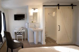 a bathroom with a sink and a toilet and a sliding door at Telegraph House Motel in Baddeck