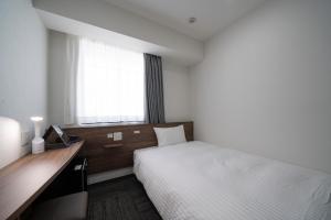 Pokój hotelowy z łóżkiem, biurkiem i oknem w obiekcie R&B Hotel Sendai Higashiguchi w mieście Sendai