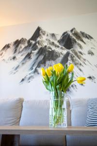 um vaso de flores amarelas numa mesa com um mural de montanha em Apartmán Háje - V srdci Tatier em Starý Smokovec