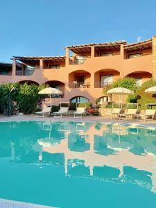 a pool in front of a hotel with chairs and umbrellas at Green Park Hotel in Porto Cervo