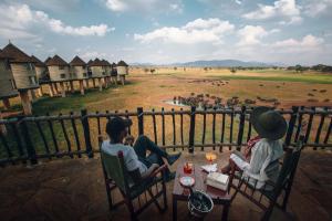 Un groupe de personnes assises à une table qui regarde un terrain dans l'établissement Salt Lick Safari Lodge, à Tsavo