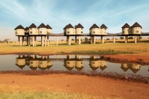 une rangée de maisons reflétées dans une masse d'eau dans l'établissement Salt Lick Safari Lodge, à Tsavo