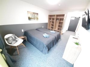 a small bedroom with a bed and a chair at Office Base Bad Vöslau MOTEL in Bad Vöslau