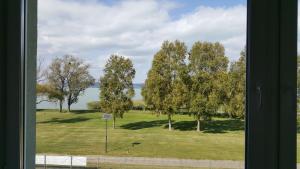 uma janela com vista para um parque com árvores e a água em Lelle Resort B26 em Balatonlelle