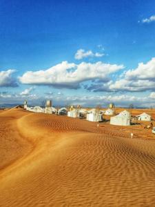 un desierto con una pequeña ciudad a lo lejos en Alsarmadi Desert Camp, en Shāhiq