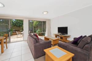 een woonkamer met 2 banken en een televisie bij Beach Resort Apartment in Port Macquarie