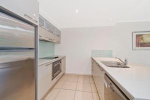 een witte keuken met een wastafel en een koelkast bij Beach Resort Apartment in Port Macquarie