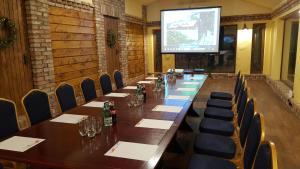 una sala de conferencias con una mesa larga, sillas y una pantalla en Dzūkijos dvaro "Oficina", en Alytus