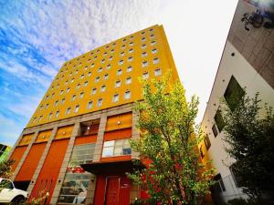 Hotel Frontier Iwaki / Vacation STAY 79264 في إيواكي: مبنى اصفر امامه شجرة