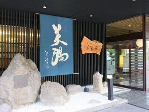 a building with a sign and rocks in front of it at Ryokan Biyunoyado in Yamanouchi