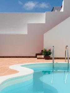 a swimming pool in front of a building at Surfers Retreat in Corralejo