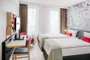 um quarto de hotel com duas camas e uma secretária em IntercityHotel Hamburg-Barmbek em Hamburgo