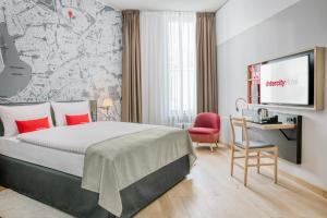 um quarto de hotel com uma cama e uma televisão de ecrã plano em IntercityHotel Hamburg-Barmbek em Hamburgo