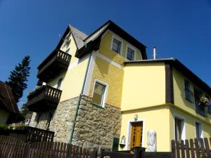 una casa amarilla y blanca con una valla en Landhaus Semmering, en Semmering