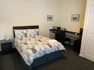 - une chambre avec un lit et un bureau avec un ordinateur dans l'établissement Ivy Cottage-Serviced accommodation, à Dyce