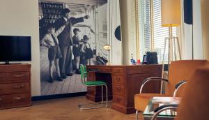 um quarto com uma secretária com uma fotografia de homens em Hotel New York by WestCord em Roterdão