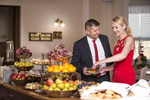 un hombre y una mujer parados frente a un buffet de frutas en Bristol Palace, en Karlovy Vary