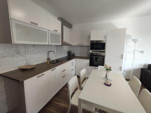 een keuken met witte kasten en een tafel met stoelen bij Hatvan Corner Apartments 2 in Debrecen