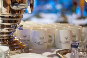 une rangée de tasses de café assise sur un comptoir avec une machine à café dans l'établissement Walliserhof Grand-Hotel & Spa Relais & Châteaux, à Saas-Fee