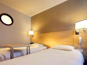 a hotel room with two beds and a table at ibis Styles Ouistreham in Ouistreham