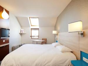 a bedroom with a white bed and a flat screen tv at ibis Styles Ouistreham in Ouistreham