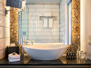 a bathroom with a large white tub on a counter at Mövenpick Hotel Wellington in Wellington