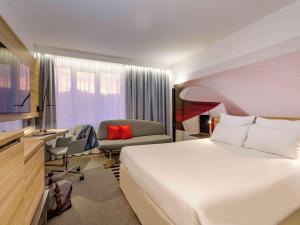 um quarto de hotel com uma cama grande e uma cadeira em Novotel Köln City em Colónia