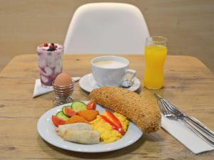 una mesa con un plato de desayuno y una taza de zumo de naranja en Ibis Győr, en Győr