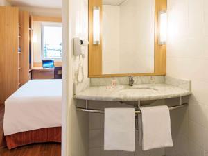 a bathroom with a sink and a bed at ibis Curitiba Aeroporto in São José dos Pinhais