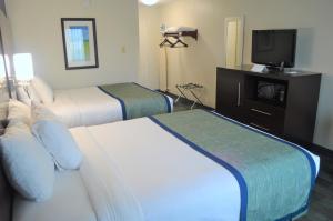 a hotel room with two beds and a flat screen tv at Falmouth Inn in Falmouth