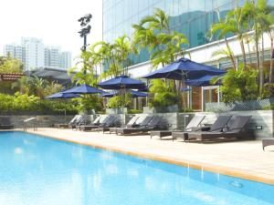 - une piscine avec des chaises longues et des parasols dans l'établissement Novotel Citygate Hong Kong, à Hong Kong