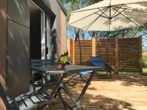 einen Tisch, Stühle und einen Regenschirm auf einer Terrasse in der Unterkunft Cottage du garlai in Bressuire