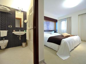 1 dormitorio con 1 cama y baño con lavamanos en Mercure Olbia, en Olbia