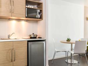 cocina con mesa, sillas y microondas en Aparthotel Adagio Access Paris Reuilly, en París