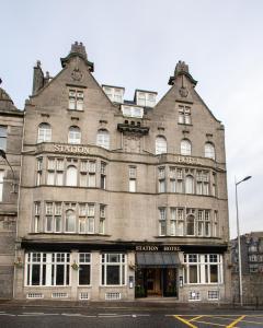 een groot gebouw op de hoek van een straat bij The Station Hotel in Aberdeen