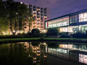 un bâtiment avec une réflexion dans l'eau la nuit dans l'établissement Mercure Hotel Dortmund Messe, à Dortmund