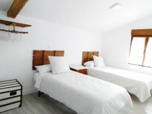 two beds in a room with white walls at Casa Rural Teresa in El Molar