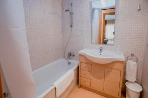 y baño con lavabo, bañera y espejo. en Apartaments Ashome, en Canillo