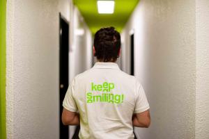 un hombre con una camisa blanca caminando por un pasillo en Hostel Le Hüb Grenoble, en Grenoble