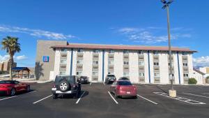 un grand bâtiment blanc avec des voitures garées dans un parking dans l'établissement Motel 6 Bullhead City, Az - Laughlin, à Bullhead City