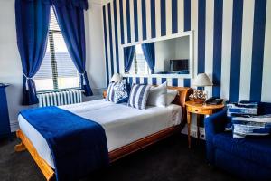 una camera con letto, sedia e specchio di Hotel D'urville Blenheim a Blenheim