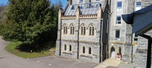 een oud stenen gebouw met een klok erop bij Loch Ness Abbey Cottages in Fort Augustus