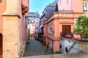 an alley in a city with pink buildings at Hotel Havana in Mainz