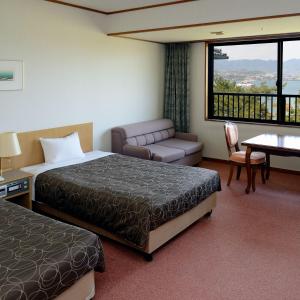 een hotelkamer met 2 bedden, een bank en een tafel bij Miyajima Morinoyado in Miyajima