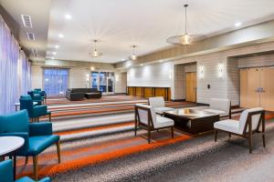 une salle d'attente avec des chaises, des tables et un piano dans l'établissement Holiday Inn & Suites - Toledo Southwest - Perrysburg, an IHG Hotel, à Perrysburg