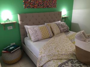 1 dormitorio con cama con almohadas y pared verde en Intra Rooms, en Olbia