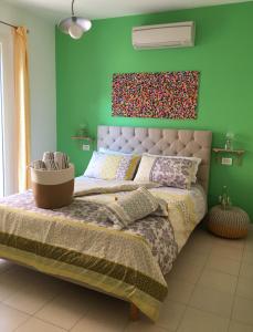 1 dormitorio con 1 cama grande y pared verde en Intra Rooms, en Olbia